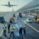 Engineers and construction professionals working together at a modern infrastructure site with a runway and roadway in the background.