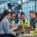 A diverse group of young rail professionals collaborating in a modern control centre with rail network screens and a train visible outside.